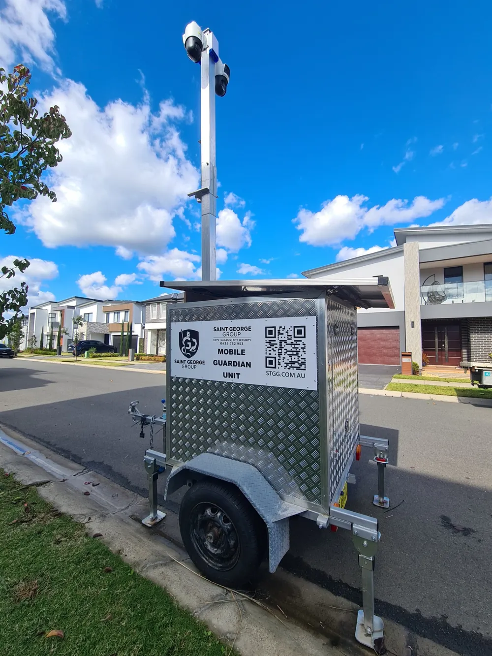 Saint George Group mobile CCTV trailer with solar panel and camera mast, parked on a suburban street.